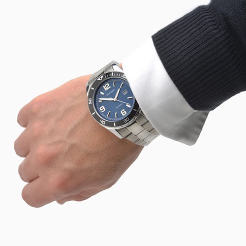 Hand wearing a watch with a blue face and silver band on a white background